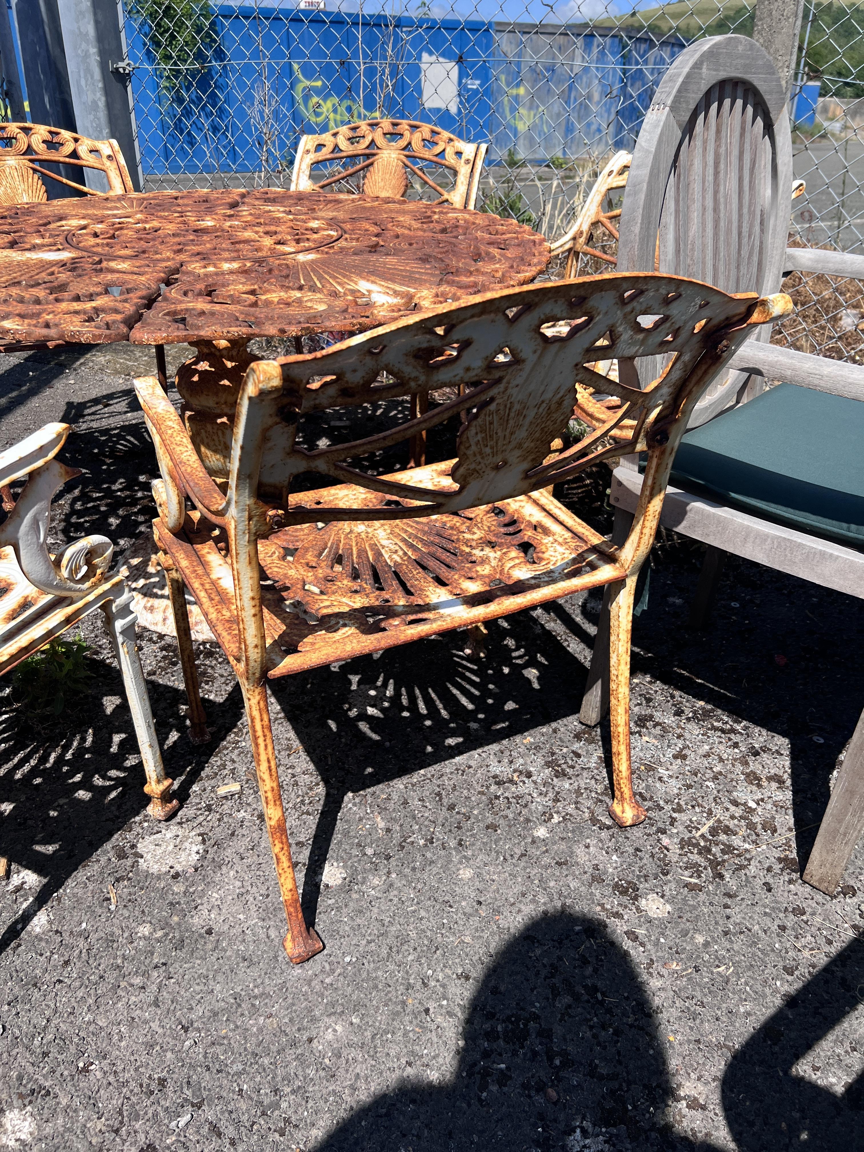 A Victorian style circular painted cast iron garden table, diameter 20cm, height 66cm and six chairs, cast with scallop shells and dolphins
